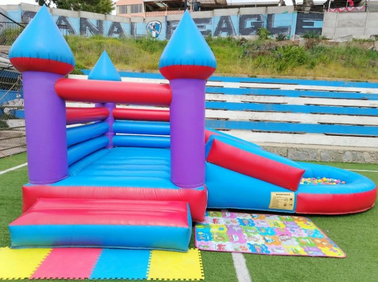 Castillo inflable morado, celeste y rojo con tobogán lateral y piscina de pelotas